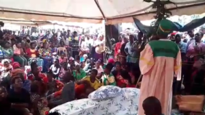 Ssababonesebwa Lubanga Kabona Kazibwe leads mourners in traditional burial ceremony. In the middle is the body of the deceased.